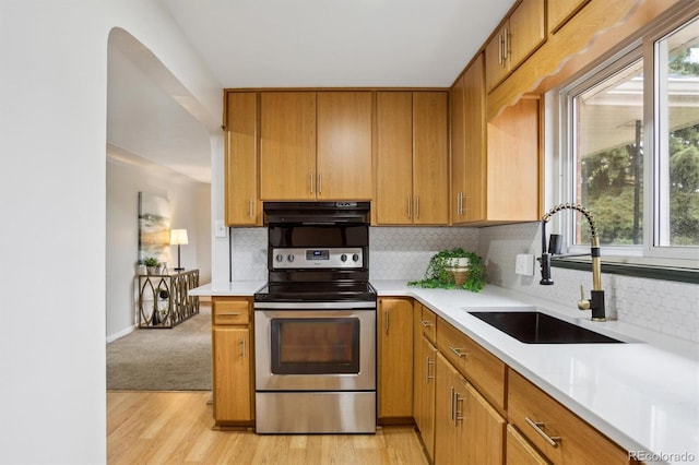 kitchen featuring stainless steel range with electric stovetop, a sink, extractor fan, light countertops, and backsplash