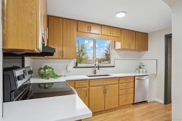 kitchen with a sink, stainless steel appliances, decorative backsplash, light wood-style flooring, and light countertops