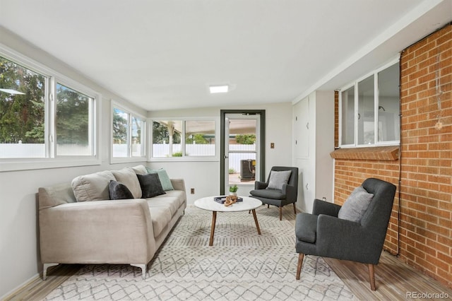 sunroom with wood finished floors, brick wall, and lofted ceiling