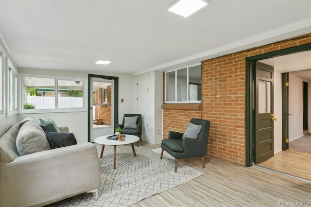 living area featuring light wood-style floors and brick wall