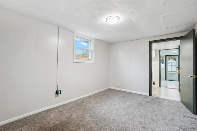 unfurnished bedroom featuring multiple windows, carpet floors, baseboards, and attic access