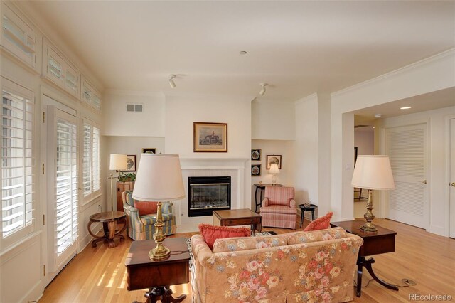 living room with crown molding, light hardwood / wood-style floors, and a tile fireplace