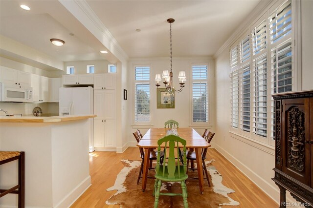 dining space with an inviting chandelier, light hardwood / wood-style flooring, and ornamental molding