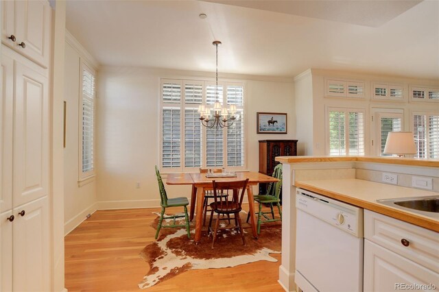 kitchen featuring white cabinetry, pendant lighting, white dishwasher, light hardwood / wood-style flooring, and a notable chandelier