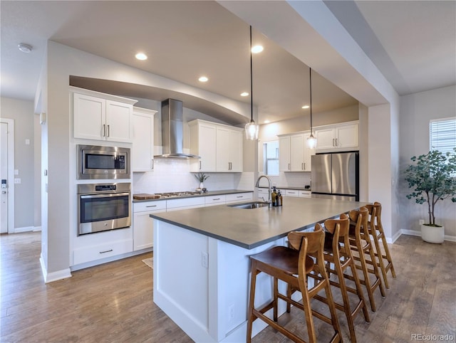 6682 Osage St, Denver, CO 80221 - kitchen featuring stainless steel appliances, a sink, wall chimney range hood, tasteful backsplash, and a center island with sink