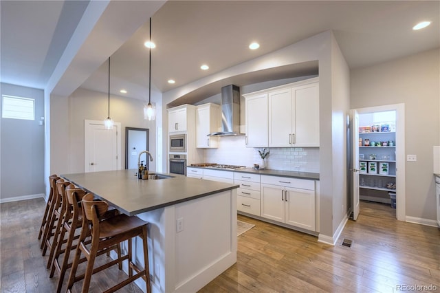 6682 Osage St, Denver, CO 80221 - kitchen featuring wall chimney range hood, stainless steel appliances, a sink, dark countertops, and recessed lighting