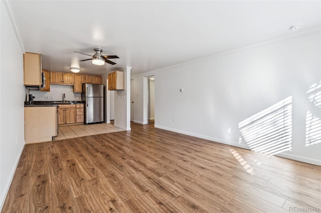 unfurnished living room with ornamental molding, sink, ceiling fan, and light hardwood / wood-style flooring