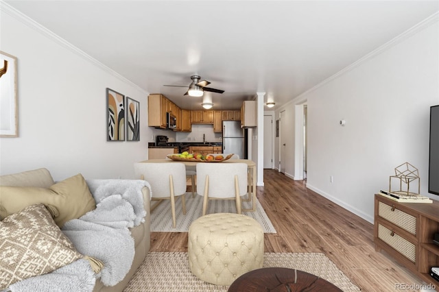 living room featuring crown molding, ceiling fan, and light hardwood / wood-style flooring