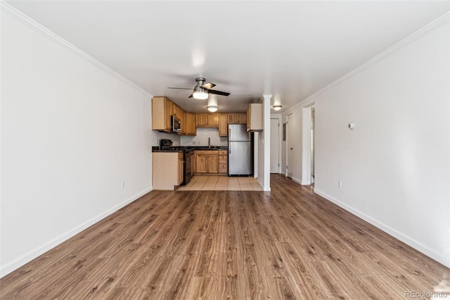 unfurnished living room featuring ornamental molding, sink, ceiling fan, and light hardwood / wood-style flooring