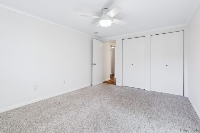 unfurnished bedroom with multiple closets, crown molding, carpet floors, and ceiling fan