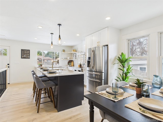 3150 S Pennsylvania St, Englewood, CO 80113 - kitchen featuring stainless steel fridge with ice dispenser, light wood-type flooring, white cabinets, hanging light fixtures, and light countertops