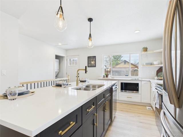 3150 S Pennsylvania St, Englewood, CO 80113 - kitchen featuring appliances with stainless steel finishes, light countertops, light wood-style flooring, white cabinets, and decorative light fixtures