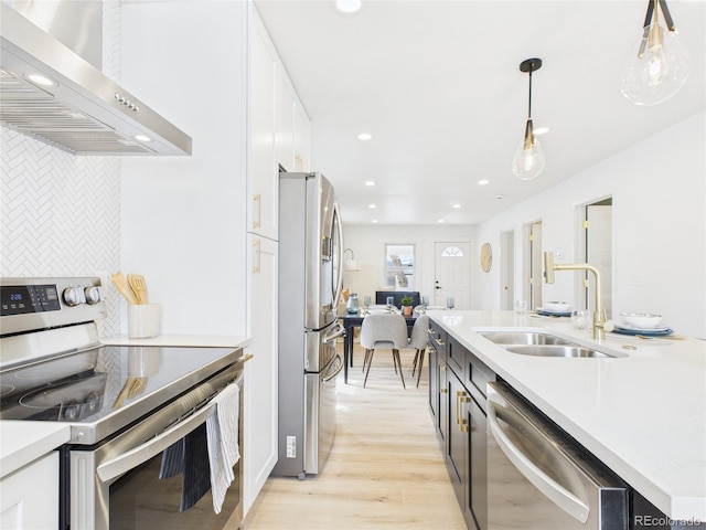 3150 S Pennsylvania St, Englewood, CO 80113 - kitchen featuring stainless steel appliances, wall chimney range hood, white cabinetry, tasteful backsplash, and hanging light fixtures