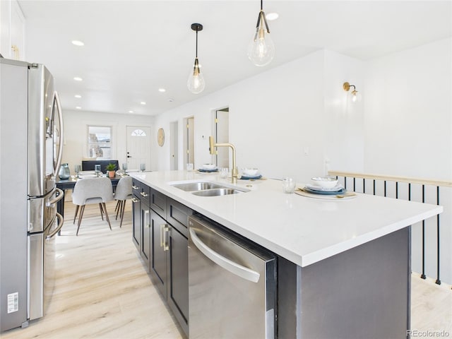 3150 S Pennsylvania St, Englewood, CO 80113 - kitchen featuring appliances with stainless steel finishes, light wood-type flooring, light countertops, decorative light fixtures, and an island with sink