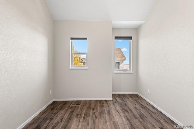 spare room with dark hardwood / wood-style flooring and a healthy amount of sunlight