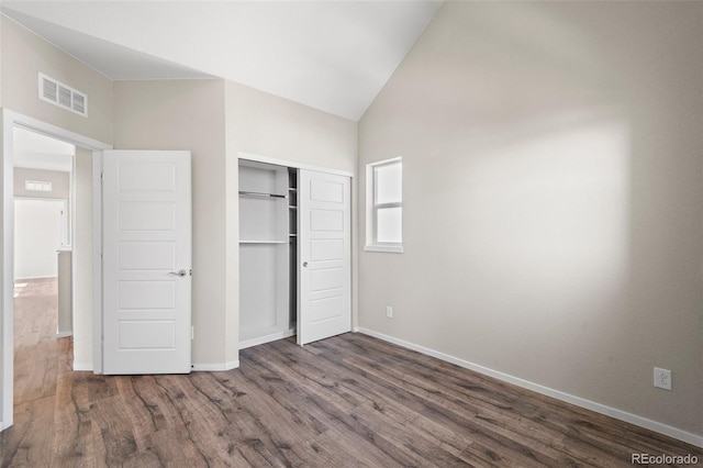 unfurnished bedroom featuring lofted ceiling, a closet, and dark wood-type flooring