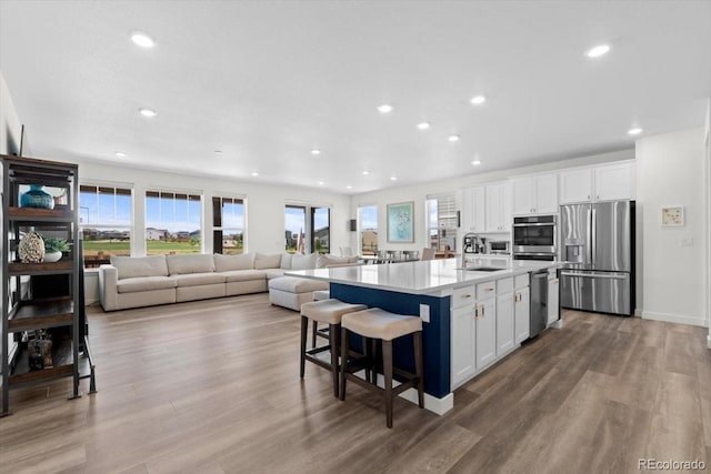 14601 Hudson St, Thornton, CO 80602 - kitchen featuring appliances with stainless steel finishes, white cabinets, recessed lighting, wood finished floors, and healthy amount of natural light