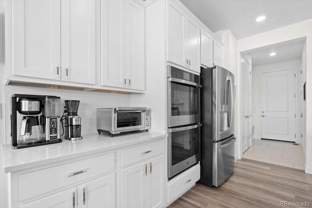 14601 Hudson St, Thornton, CO 80602 - kitchen with stainless steel appliances, white cabinetry, light wood finished floors, recessed lighting, and light stone counters