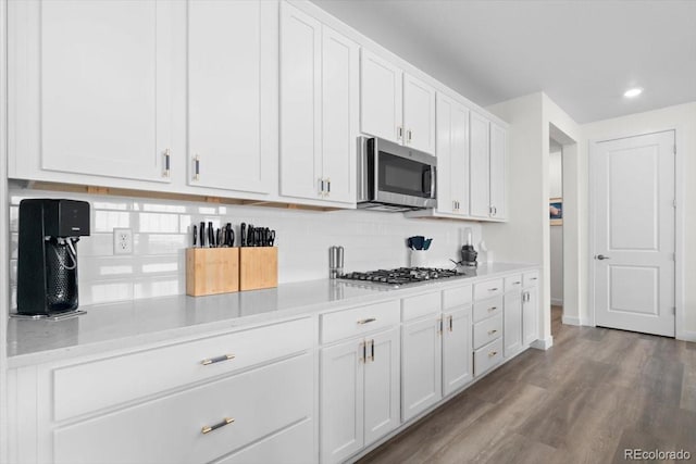 14601 Hudson St, Thornton, CO 80602 - kitchen with stainless steel appliances, decorative backsplash, white cabinets, light countertops, and wood finished floors