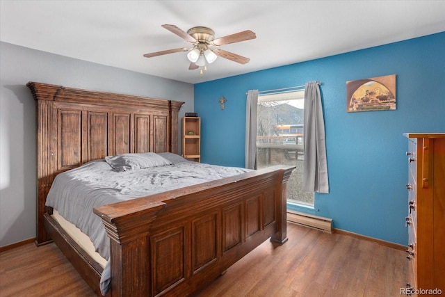 bedroom with hardwood / wood-style floors, a baseboard radiator, and ceiling fan