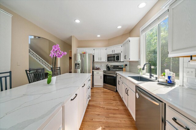 10610 Winterflower Way, Parker, CO 80134 - kitchen featuring appliances with stainless steel finishes, a sink, light stone counters, tasteful backsplash, and white cabinetry