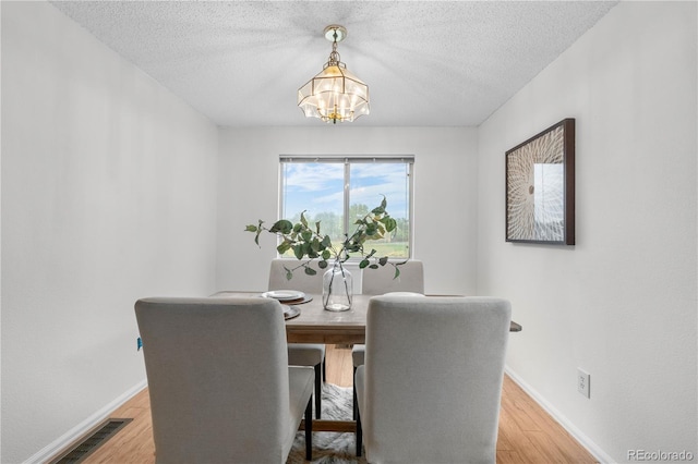 1741 W 131st Ct, Denver, CO 80234 - dining space featuring a chandelier, light wood-style floors, and a textured ceiling