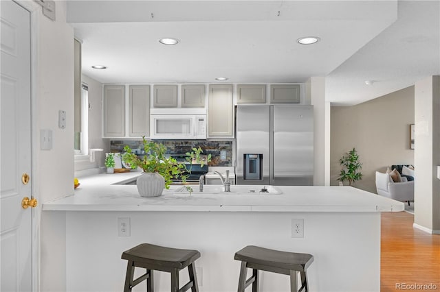 1741 W 131st Ct, Denver, CO 80234 - kitchen featuring stainless steel fridge with ice dispenser, white microwave, a peninsula, light countertops, and recessed lighting