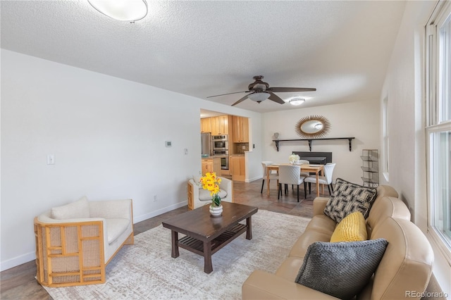 living room featuring ceiling fan and a textured ceiling