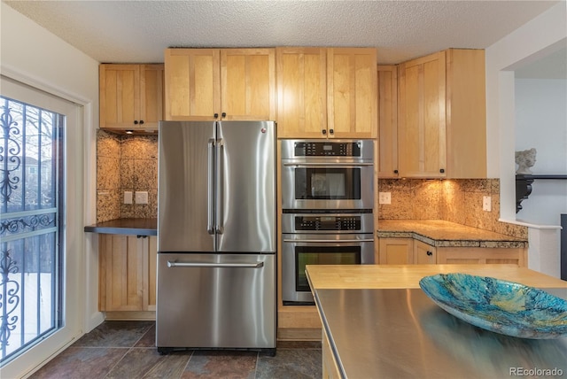 kitchen featuring light brown cabinetry, tasteful backsplash, stainless steel appliances, and a textured ceiling