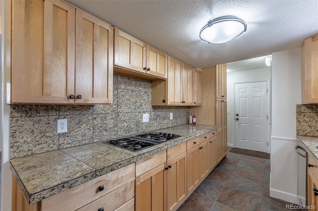 kitchen with backsplash, gas cooktop, a textured ceiling, and light brown cabinets