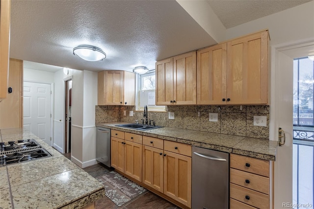 kitchen featuring light brown cabinetry, sink, decorative backsplash, stainless steel appliances, and a textured ceiling