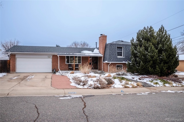 tri-level home with brick siding, roof with shingles, a chimney, an attached garage, and driveway