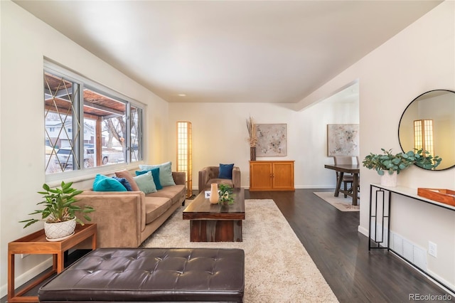 living room with dark wood-type flooring and baseboards