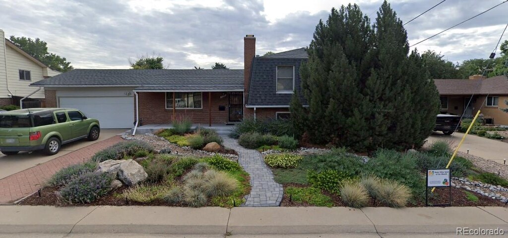 10902 Bannock St, Northglenn, CO 80234 - split level home featuring an attached garage, brick siding, driveway, a chimney, and roof with shingles