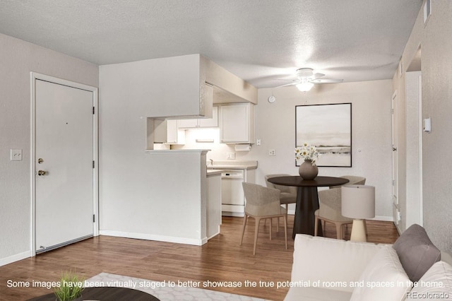 kitchen featuring white cabinetry, wood finished floors, a textured ceiling, and white dishwasher