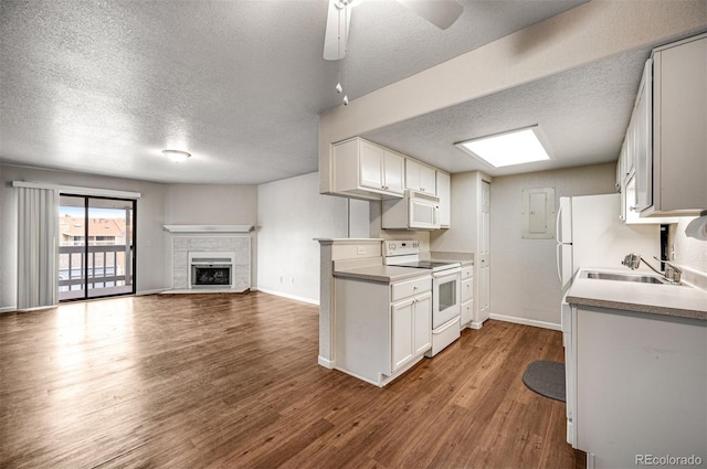 kitchen with white appliances, wood finished floors, baseboards, a fireplace, and a sink