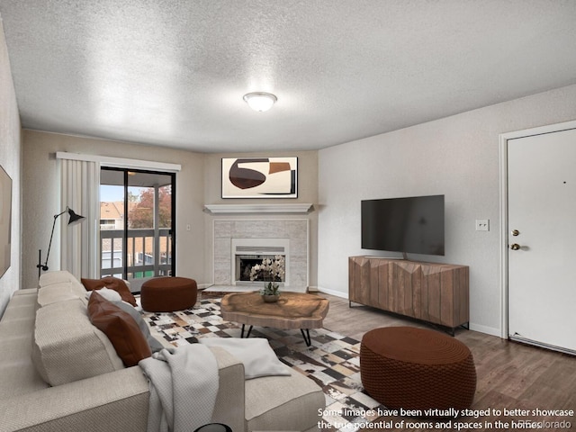 8335 Fairmount Dr Unit 9-206, Denver, CO 80247 - living area with a textured ceiling, a tiled fireplace, and wood finished floors
