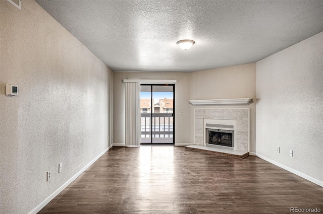 8335 Fairmount Dr Unit 9-206, Denver, CO 80247 - unfurnished living room with baseboards, a tiled fireplace, wood finished floors, and a textured wall