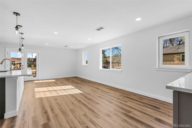 unfurnished living room featuring light wood-type flooring, a healthy amount of sunlight, and sink