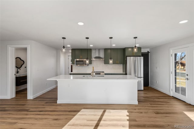 kitchen with decorative light fixtures, appliances with stainless steel finishes, wall chimney exhaust hood, and a barn door