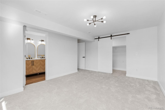 interior space featuring a notable chandelier, a barn door, a closet, light colored carpet, and connected bathroom