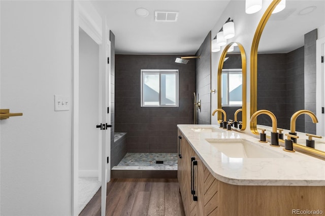 bathroom with a tile shower, hardwood / wood-style flooring, and vanity