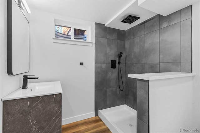 bathroom featuring a tile shower, wood-type flooring, and vanity