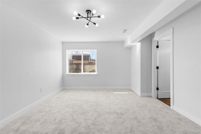 carpeted empty room with a notable chandelier