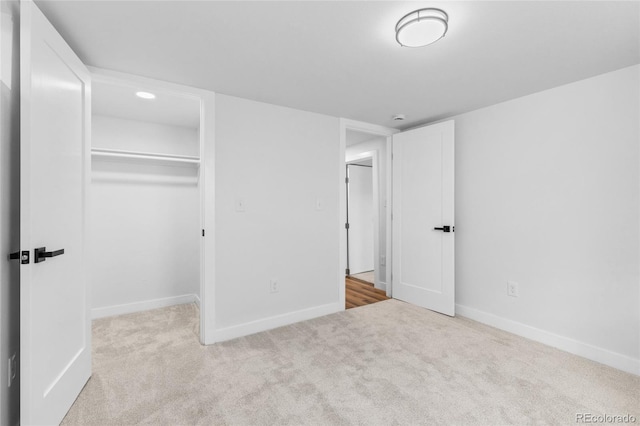 unfurnished bedroom featuring light colored carpet, a closet, and a walk in closet