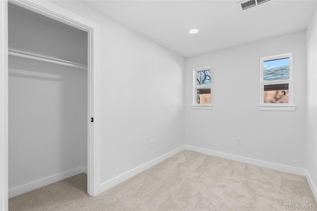 unfurnished bedroom featuring light colored carpet and a closet