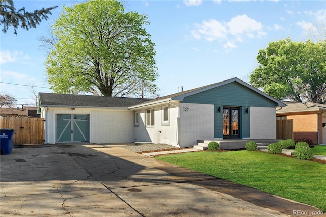 view of front of house with brick siding, concrete driveway, an attached garage, a front yard, and fence