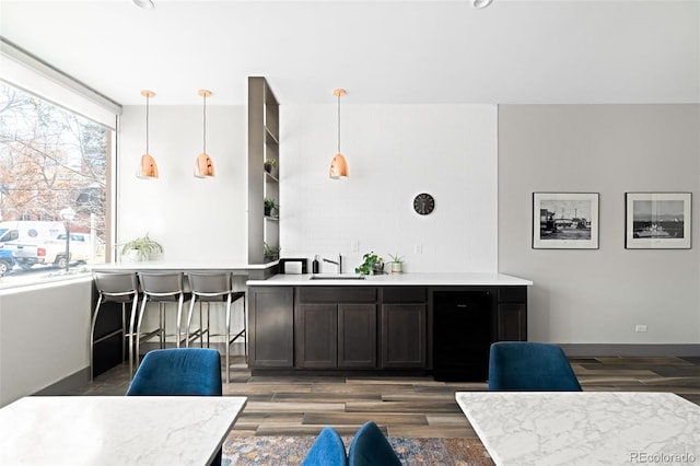 interior space featuring wood finished floors, baseboards, light countertops, a sink, and decorative light fixtures