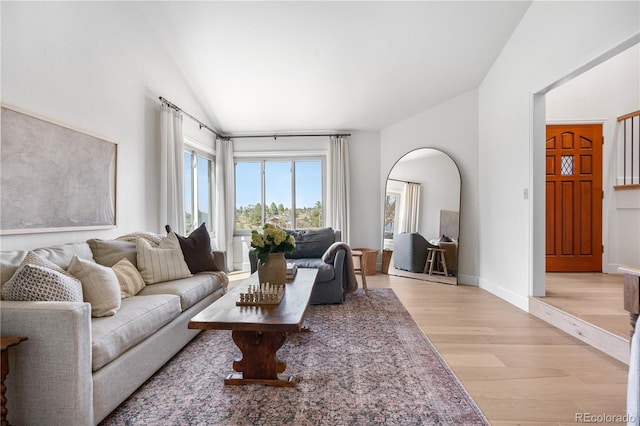 living area with light wood-style floors, baseboards, and lofted ceiling