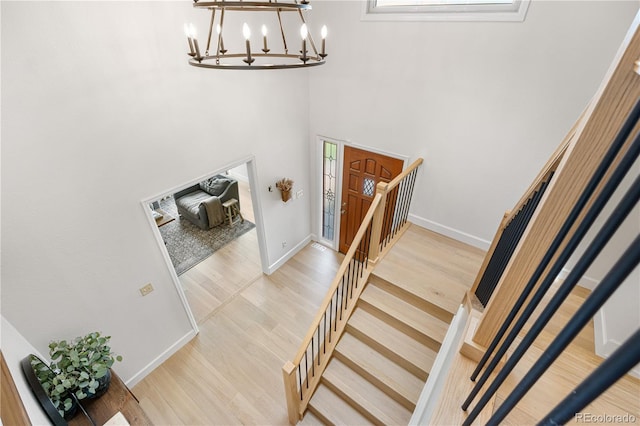 stairway featuring baseboards, an inviting chandelier, and wood finished floors